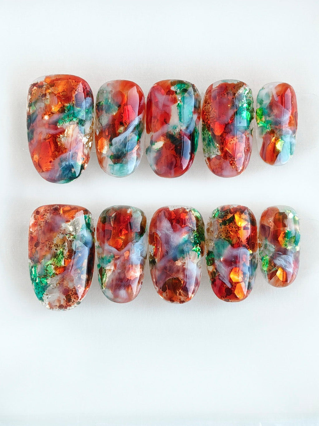 Colorful nail art designs in a clear plastic case on a white background