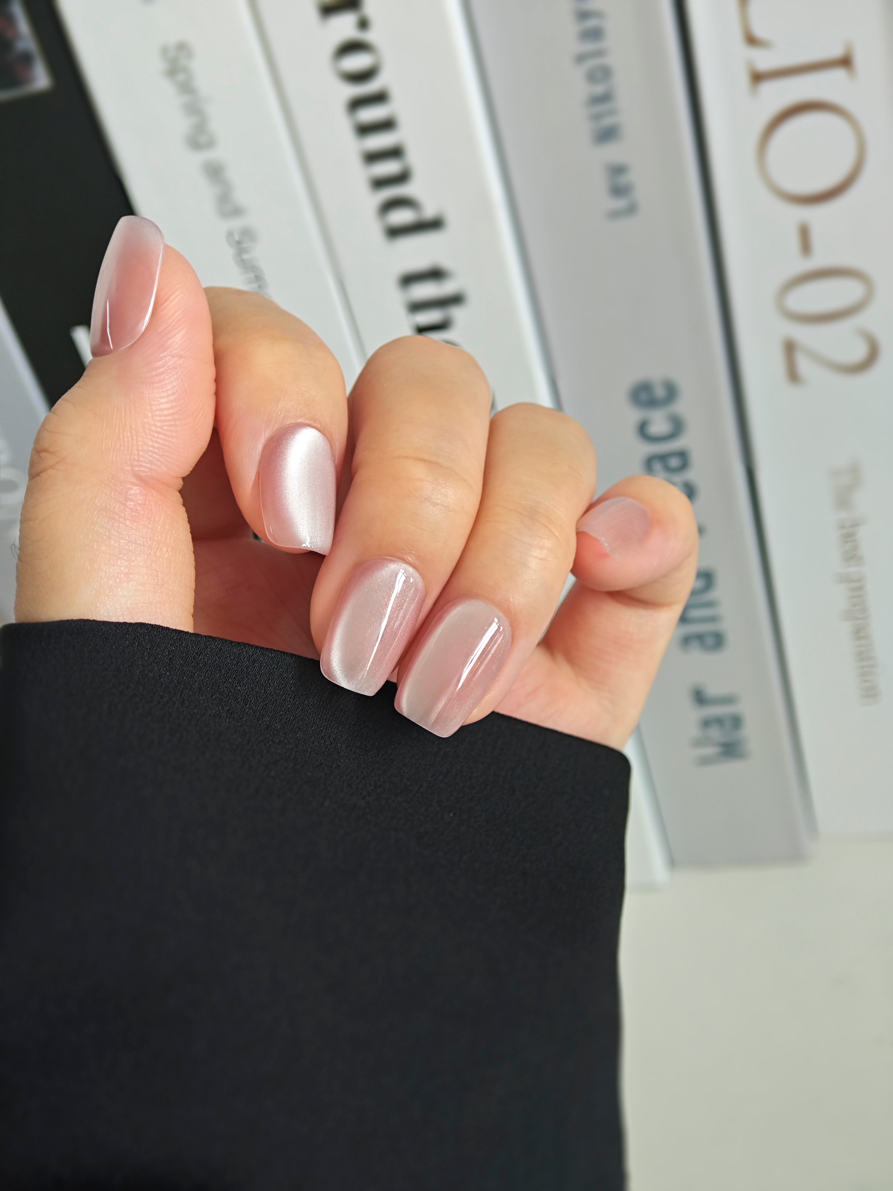 Hand with light pink nail polish holding a magazine