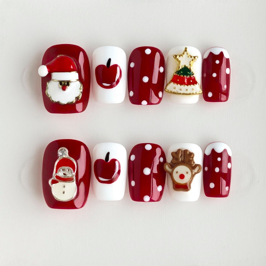 Christmas-themed nail art with Santa Claus, reindeer, and Christmas tree designs on a white background.